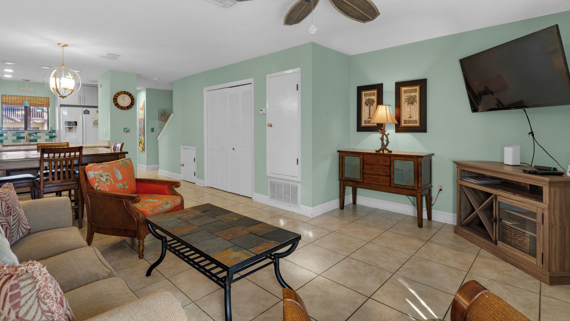 A living room with a dining area, a TV, and a kitchen in the background.