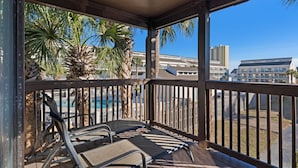 A covered outdoor area with metal chairs and a pool in the background.