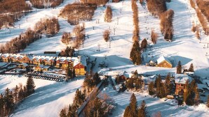 A snow-covered ski resort with multiple buildings, ski lifts, and a mountain backdrop.