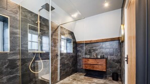 Une salle de bain moderne avec une douche en verre, un meuble-lavabo en bois et un sol carrelé en pierre.