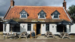 Un pub traditionnel appelé « The Stag », avec un toit recouvert de tuiles, deux petites fenêtres en lucarne et une enseigne.