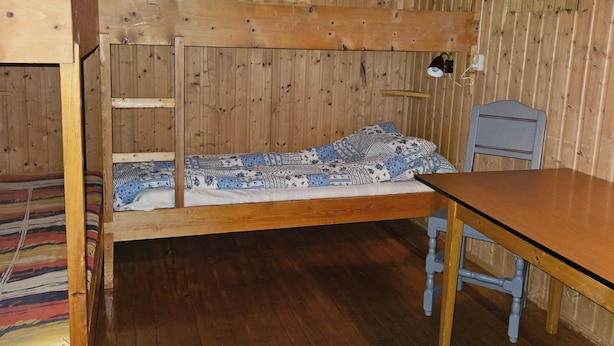 A bunk bed with a wooden headboard, a small table, and a chair. - Fossen Camping Fagernes (Innlandet)