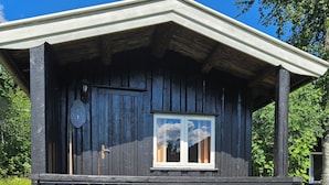 A wooden cabin with a porch, two chairs, a table, and a window. - Fossen Camping Fagernes (Innlandet)
