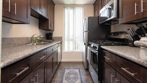 Una cocina moderna con armarios de madera oscura, encimeras de granito, electrodomésticos de acero inoxidable y una alfombra estampada.