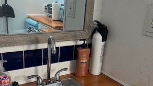 Eine Küche mit Spüle aus Edelstahl, einer Holzarbeitsplatte und einer blau-weißen Küchenrückwand.