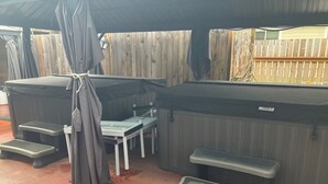 Ein überdachter Außenbereich mit mehreren Whirlpools und Hockstühlen.