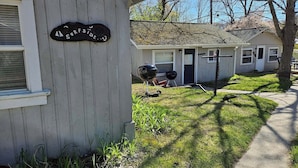 A small, single-story building with a porch and a grill outside. - Cozy Beachcomber Cottage on Great Lake Huron (Ausable Township)