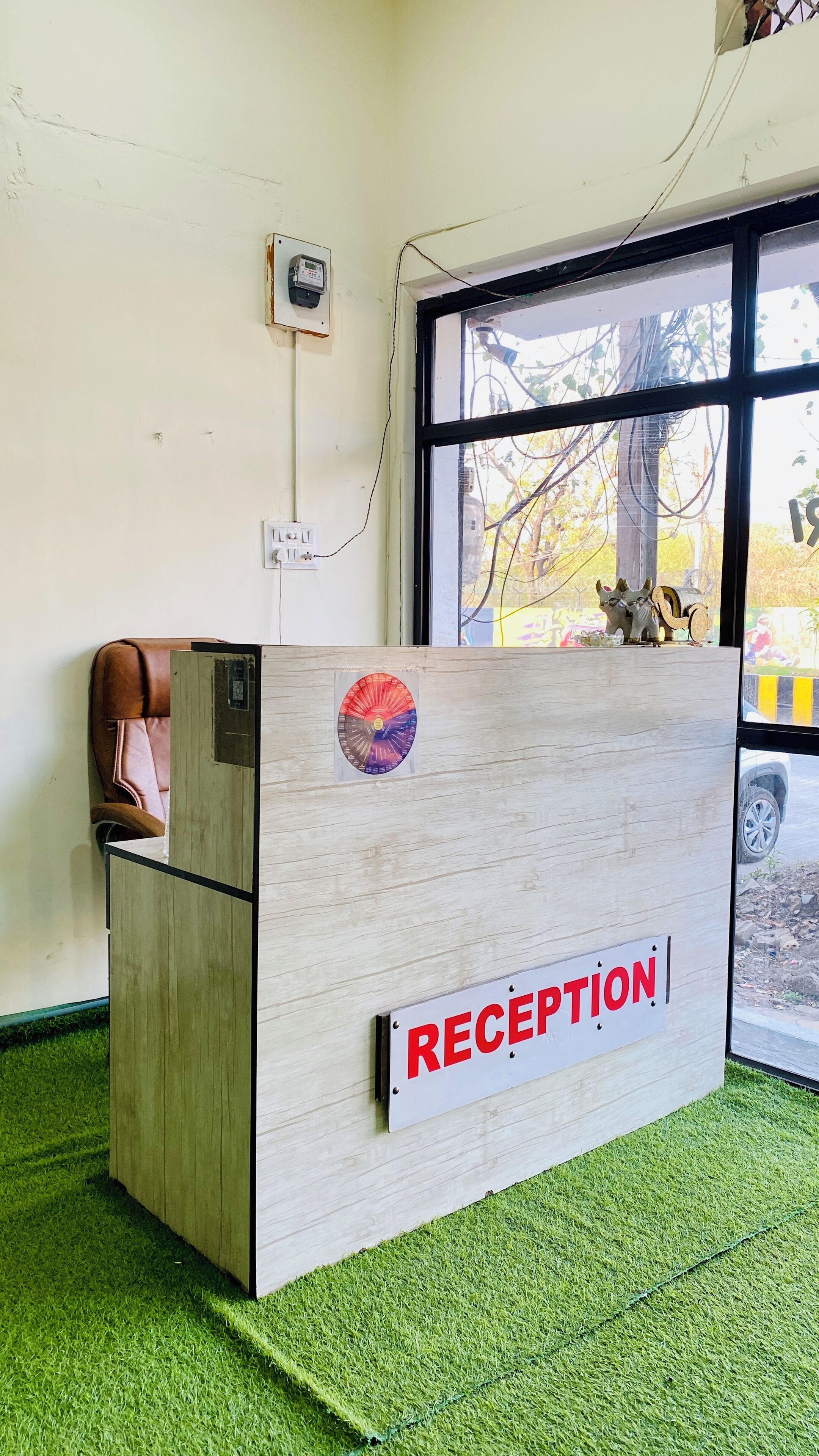 A reception desk with a 'RECEPTION' sign, a telephone, and a window with a view of the outside.