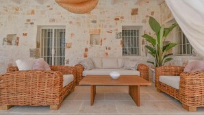 A cozy room with a stone wall, wicker furniture, and a hanging light fixture. - Tenuta Maria Vittoria - Private pool & garden (Ostuni)