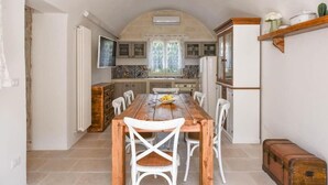 A kitchen with a wooden table and white chairs, a refrigerator, and a window with curtains. - Tenuta Maria Vittoria - Private pool & garden (Ostuni)