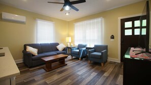 Una sala de estar con sofá, sillones, una mesa de centro y un mueble para la televisión.