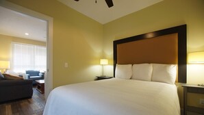 Una habitación de hotel con una cama grande, una mesita de noche con lámpara, una silla y un escritorio.