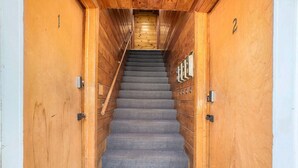A wooden staircase with carpeted steps leading to a wooden ceiling.