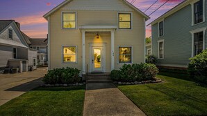 A two-story house with a front porch, a visible number '105' on the door, and a well-maintained lawn.