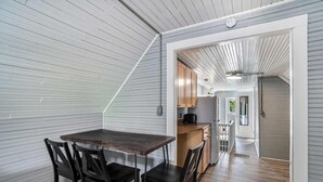Un comedor con una mesa y sillas de madera, una cocina al fondo y un pasillo que lleva a otra habitación.