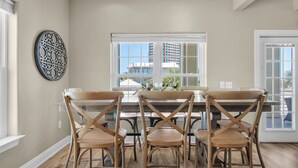 Un comedor con una mesa y cuatro sillas, un adorno en la pared y una ventana con vista a edificios.