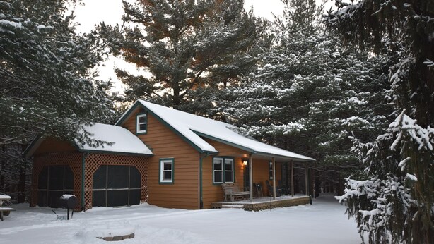 A wooden cabin with a snow-covered roof, surrounded by evergreen trees. - Woodland view-Cedar Cottage (Laurelville)