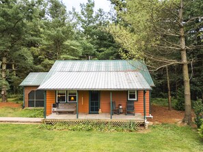 Une cabane rustique avec un toit en métal, un revêtement extérieur en bois et une véranda équipée de sièges.