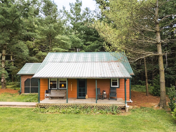 A rustic cabin with a metal roof, wooden exterior, and a porch with seating. - Woodland view-Cedar Cottage (Laurelville)