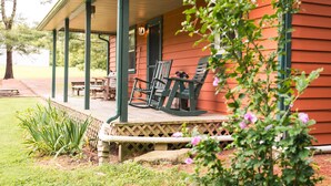 A porch with wooden chairs and a table, surrounded by a garden with plants and flowers. - Woodland view-Cedar Cottage (Laurelville)