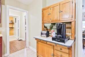 A kitchen with wooden cabinets, a countertop, a toaster, a coffee maker, and a kettle.