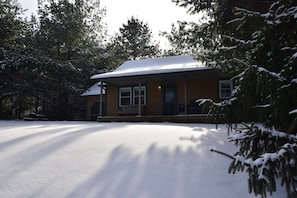 A snow-covered building with a porch and a covered entryway. - Woodland view-Cedar Cottage (Laurelville)