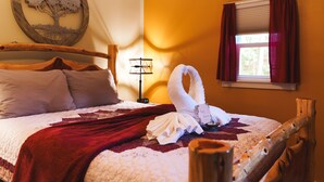A neatly made bed with a red blanket, a wooden headboard, and a wall-mounted tree artwork. - Woodland view-Cedar Cottage (Laurelville)