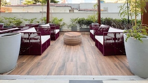 A covered outdoor seating area with wicker furniture and potted plants. - Essence Studio Vila Mariana | Air Conditioning, Wi-Fi & Vila Mariana Metro (São Paulo)