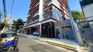 A tall, multi-story building with a modern design, featuring a prominent entrance with glass doors and a red and white color scheme. - Essence Studio Vila Mariana | Air Conditioning, Wi-Fi & Vila Mariana Metro (São Paulo)