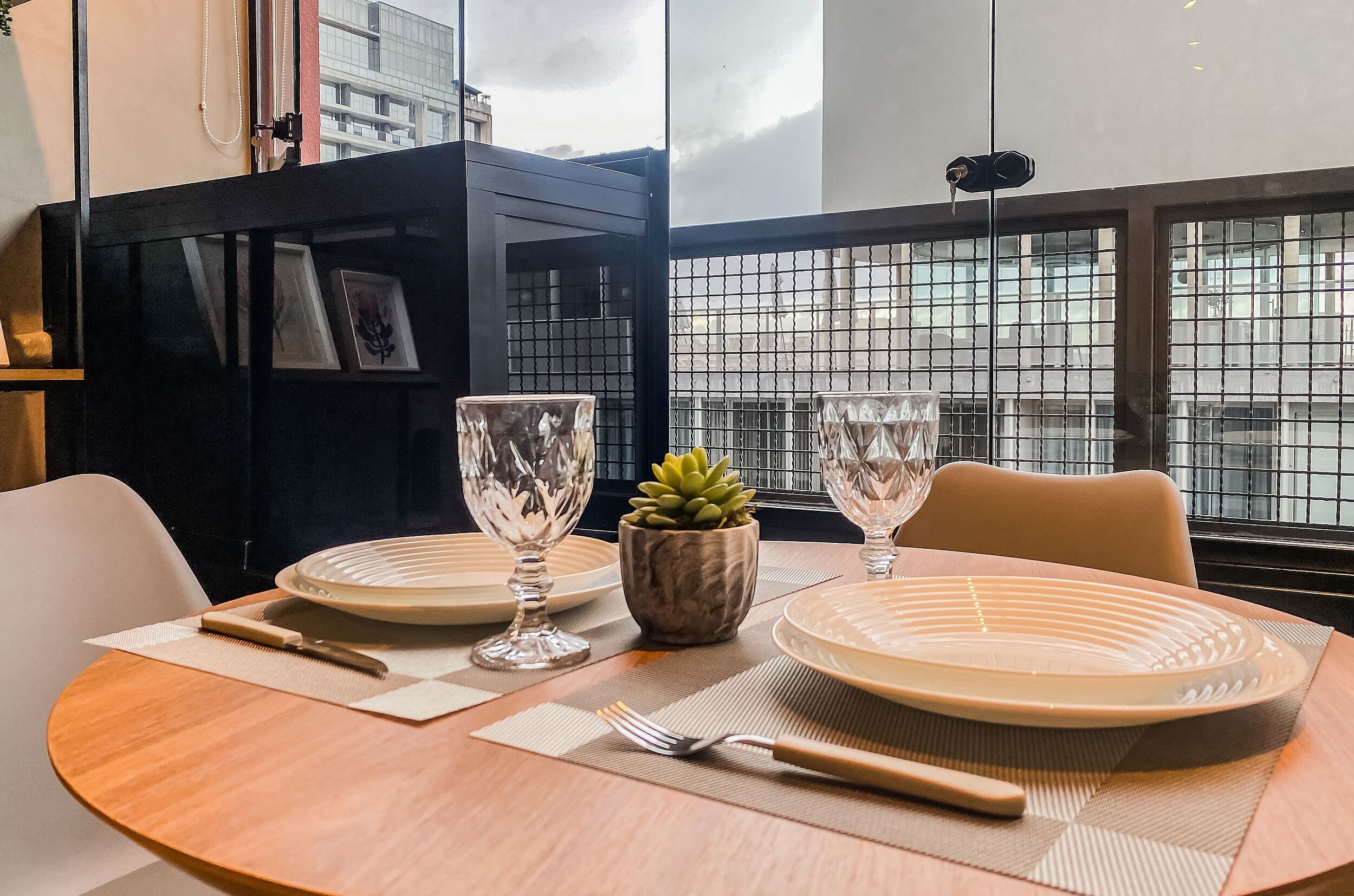 Une table à manger dressée avec des assiettes, des couverts et une petite plante en pot.