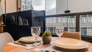 Een eettafel gedekt met borden, bestek en een kleine potplant.