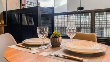 Une table à manger dressée avec des assiettes, des couverts et une petite plante en pot.