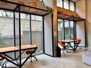 Un espace de bureau moderne avec des cloisons en verre, des tables en bois et des chaises orange.