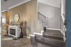 A modern interior with a fireplace, a staircase, and a blue door. - Entire Home 3 bedroom 2.5 bathroom in Avondale Arizona (Avondale)