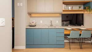 Una cocina moderna con armarios azules, encimera de granito y un comedor con dos sillas y una mesa de madera.