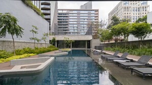 A modern swimming pool with tiled edges, surrounded by lounge chairs and greenery. - VN Millenium Faria Lima (Sao Paulo)