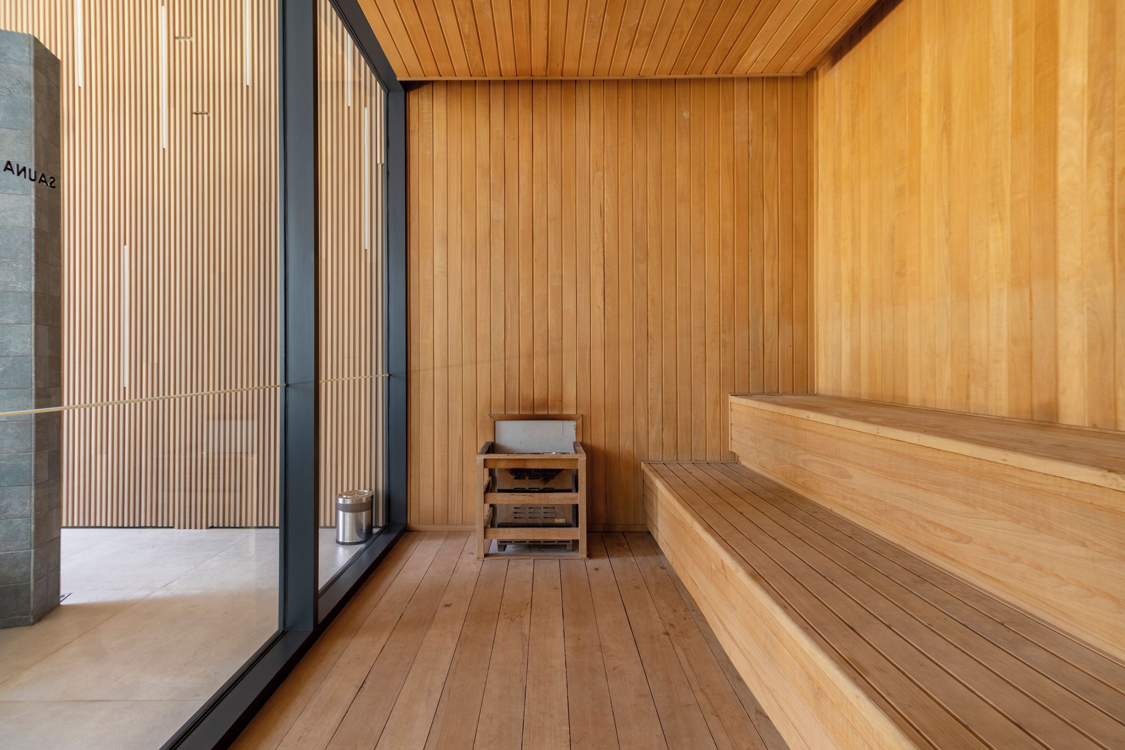 Une salle de spa moderne avec un lambris en bois, un petit banc en bois et une cloison en verre.