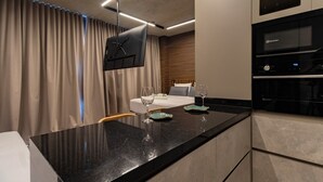 A modern hotel room with a bed, a dining area with a black countertop, and a built-in oven. - VN Millenium Faria Lima (Sao Paulo)