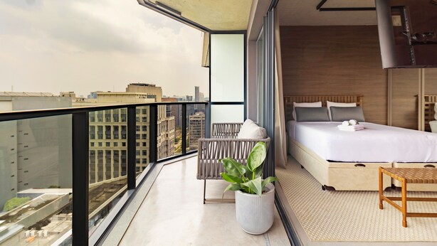 A modern bedroom with a large bed, a small table, and a potted plant. - VN Millenium Faria Lima (Sao Paulo)