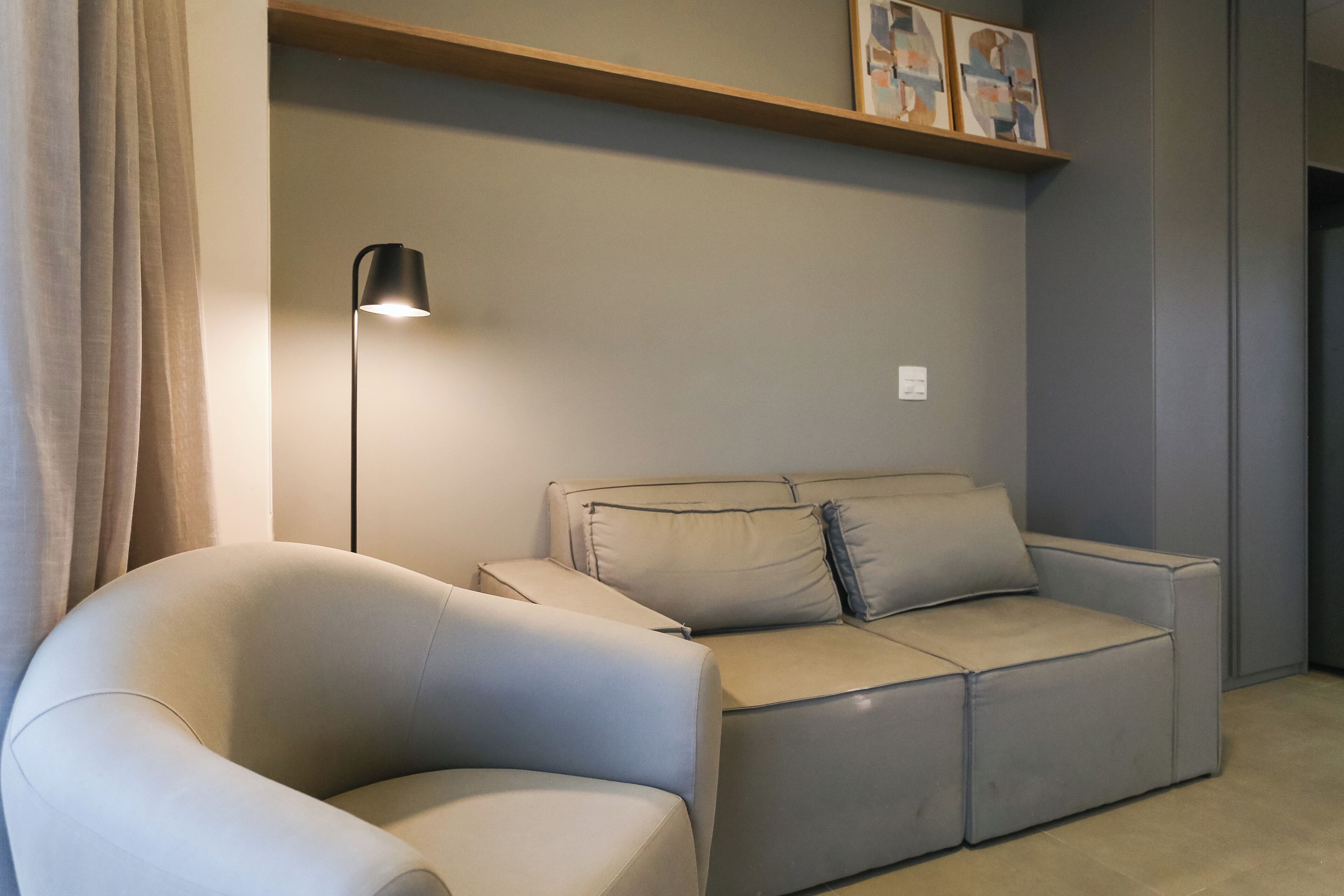 Uma sala de estar moderna com um sofá, um abajur e obras de arte na parede.