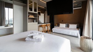 A modern hotel room with a large bed, a separate sleeping area, a kitchen area with bar stools, and a flat-screen TV mounted on the wall. - VN Millenium Faria Lima (Sao Paulo)