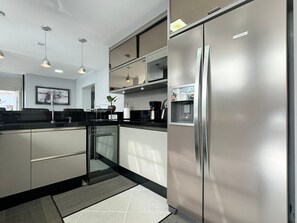 A modern kitchen with stainless steel appliances, a built-in coffee maker, and pendant lighting. - Casa Moderna e Aconchegante  (Florianopolis)