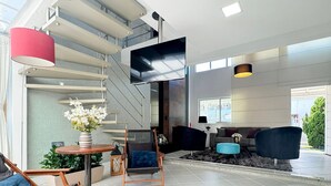 A modern living room with a staircase, a flat-screen TV, and a large window. - Casa Moderna e Aconchegante  (Florianopolis)