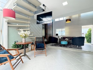 A modern living room with a staircase, a flat-screen TV, and a large window. - Casa Moderna e Aconchegante  (Florianopolis)