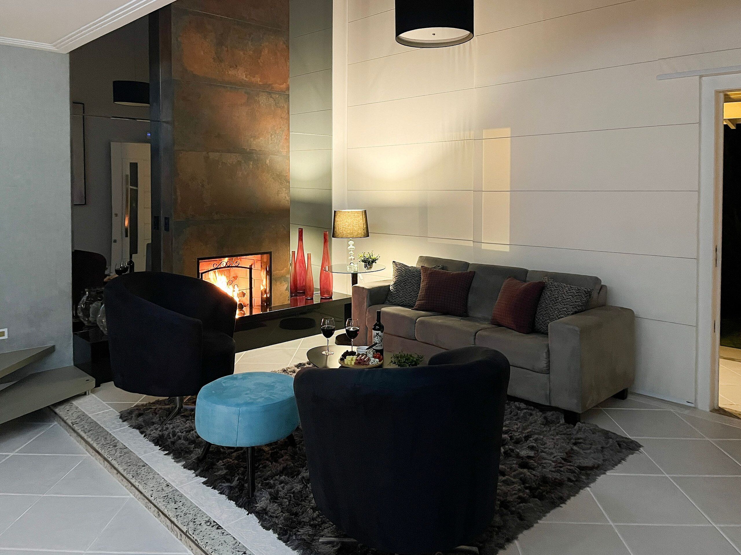 Een moderne woonkamer met een open haard, een bank, twee fauteuils en een salontafel.