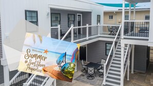 A multi-level residential building with a balcony, outdoor seating, and a staircase. - Shore Thing · Walk to Beach · Sleeps 6 Guest Favorite Superhost (North Wildwood)