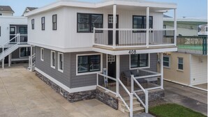 A two-story residential building with a balcony, a front porch, and a staircase leading to the entrance. - Shore Thing · Walk to Beach · Sleeps 6 Guest Favorite Superhost (North Wildwood)