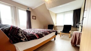 Ein Schlafzimmer mit einem Bett, einem Sessel, einem kleinen Tisch und einem Fenster.