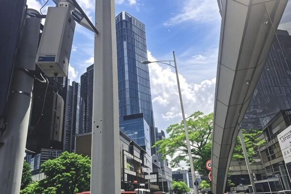 A cityscape with modern buildings, a clear sky, and a street with traffic lights.