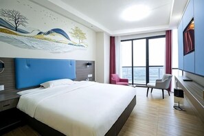 Une chambre d’hôtel avec un grand lit, un bureau, une chaise, une télévision et une fenêtre avec des rideaux.